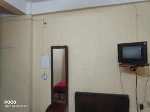 a room with a mirror and a tv and a chair at HOTEL SUKHMANI in Guwahati
