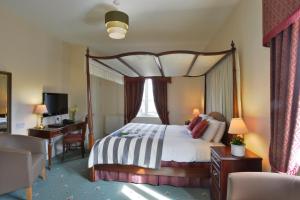 a bedroom with a canopy bed with a desk and a chair at Taunton House Hotel in Taunton +14 photos