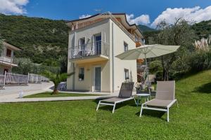 uma casa com duas cadeiras, uma mesa e um guarda-sol em La Pervinca Apartments em Malcesine