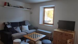 een woonkamer met een bank en een televisie bij Briançon-Serre Chevalier - Apt 3 pièces - 4 à 6 couchages - Au calme-Jardin mis à dispo in Briançon