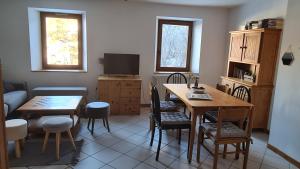 a living room with a table and chairs and a television at Briançon-Serre Chevalier - Apt 3 pièces - 4 à 6 couchages - Au calme-Jardin mis à dispo in Briançon +8 photos