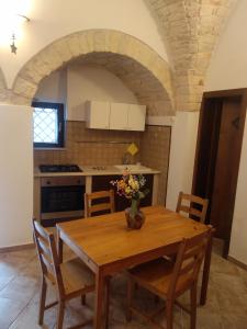 uma cozinha com uma mesa de madeira com cadeiras e uma cozinha com um arco em Soggiornare In Centro em Alberobello
