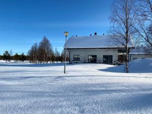 un campo cubierto de nieve con un edificio blanco con un poste de luz en Levi Kaakkuri 6 en Levi