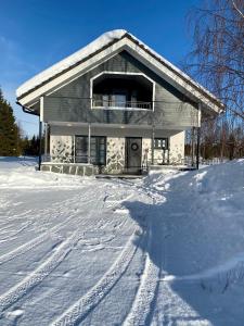 une maison dans la neige avec des pistes dans la neige dans l'établissement Levi Kaakkuri 6, à Levi