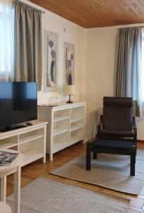 un salon avec une télévision et une chaise dans l'établissement Schollers Restaurant & Hotel, à Rendsburg
