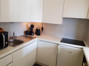 a small kitchen with white cabinets and a sink at Casa Quatre-Mains Westende in Middelkerke +14 photos
