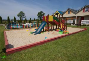 un parque infantil con un tobogán en la arena en Kolorowe Domki en Jarosławiec