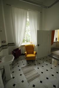 a bathroom with a yellow chair and a sink at Pałac Nakomiady in Nakomiady