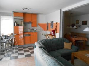 un salon avec un canapé et une cuisine avec des armoires orange dans l'établissement Ferienhaus im Westerwald Eichsfeld, à Ershausen