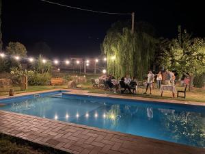 um grupo de pessoas sentadas à volta de uma mesa à beira de uma piscina à noite em Agriturismo Colle Vento em Suvereto