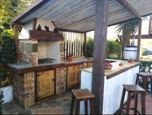 an outdoor kitchen with a stone stove and stools at Casa Roiz in Santillana del Mar