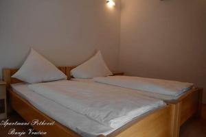 a bed with white sheets and pillows on it at APARTMANI PETKOVIC in Teslić