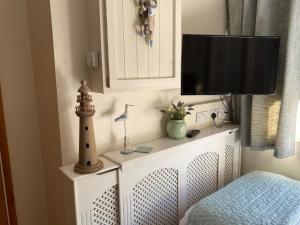 a tv on top of a white dresser with a lighthouse at The Peels B&B in Lowestoft