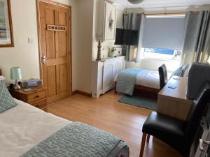 a bedroom with a bed and a desk and a window at The Peels B&B in Lowestoft
