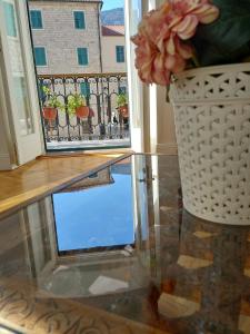 a glass table with a window and a vase with a flower at Old Town Sea Gate Apartment in Kotor