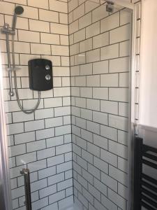a white tiled shower with a black soap dispenser at Glenthorne Guest House in Tenby