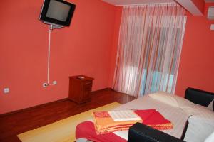a red room with a bed and a tv on the wall at 500 Meters from Grate Beach, App 1 in Ulcinj
