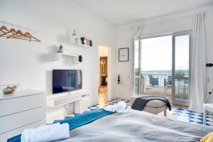 1 dormitorio blanco con 1 cama grande y TV en La Baia di Ortigia, en Siracusa