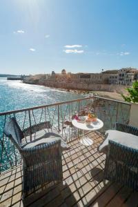 a balcony with chairs and a table and the water at La Baia di Ortigia in Syracuse