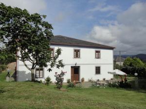une maison blanche avec un arbre dans la cour dans l'établissement Casa Rural Vila Pomar, à Ribadeo