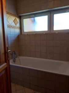 een badkamer met een bad en een raam bij KataKunyhó in Keszthely +19 foto's