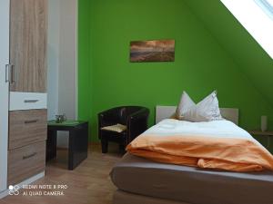 een groene slaapkamer met een bed en een stoel bij Ferienwohnung "An der Geest 2" in Buxtehude