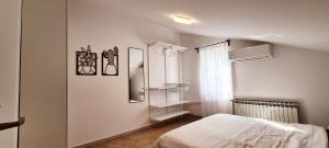 a white bedroom with a bed and a window at Studio Dora Malinska in Malinska