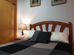 a bed with black and white pillows and a lamp at Apartamento de vacaciones in Torrevieja