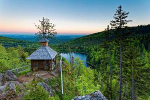 eine Hütte an der Seite eines Berges mit einem See in der Unterkunft Ferienwohnung im Landhaus am Nationalpark in Ludwigsthal