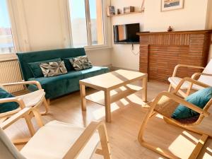 - un salon avec un canapé vert et des chaises dans l'établissement Appartement La Rafale - accès privé plage - jardin - arrivée autonome, à Gravelines