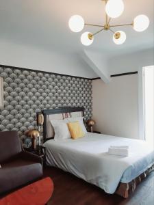 a bedroom with a large bed and a chair at Saint Charles Hôtel & Coliving Biarritz in Biarritz