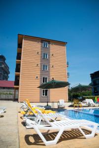 una piscina con sedie e ombrelloni di fronte a un edificio di Guesthouse Gio a Gonio