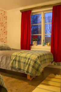 スカーラにあるHallebergs Bed&Breakfastのベッドルーム1室(赤いカーテンと窓付きのベッド1台付)