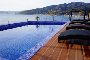 ein Pool mit Stühlen neben einem Wasserkörper in der Unterkunft HOTEL HIMALAYA SEA in Ito