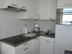 a small kitchen with white cabinets and a sink at Studio Penthouse Nieuwpoort in Nieuwpoort +4 photos