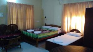 een slaapkamer met 2 bedden en een tafel en stoelen bij Karthika Plaza Resort Pvt Ltd in Varkala