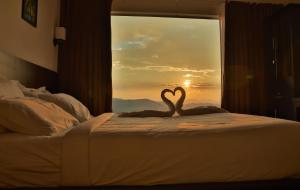 a couple of swans sitting on a bed in front of a window at Peakaavu Cottages in Idukki