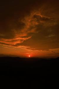 a sunset with the sun in the sky at Peakaavu Cottages in Idukki