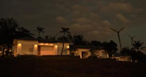 a house with windmills in the background at night at Peakaavu Cottages in Idukki