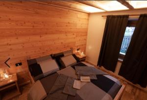 - une chambre avec 2 lits dans une pièce dotée de murs en bois dans l'établissement Appartamenti al Ciariè, 