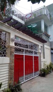 una puerta de garaje roja en una casa con balcón en Ellens Homestay en Irosin