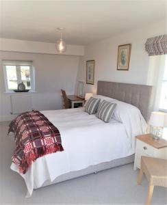 a bedroom with a white bed with a blanket on it at Crow's Nest in Somerford Keynes
