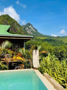 a woman in a white dress standing next to a swimming pool at Waterfall Accomodation in Port Glaud