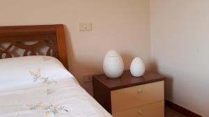zwei weiße Vasen auf einer Kommode neben einem Bett in der Unterkunft PR home in San Ferdinando