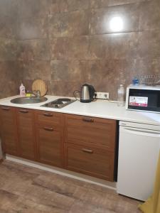 a kitchen with a stove and a sink and a microwave at Apartment Sports Palace Просторная квартира рядом Дворец Спорта in Kharkiv