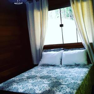 a bedroom with a bed with a window and pillows at Recanto Della Mata in Venda Nova do Imigrante