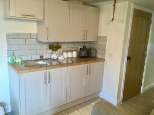 una cocina con armarios blancos y fregadero en YETHOLM BOTHY en Town Yetholm