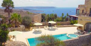 un complejo con piscina y vistas al océano en Ferrieha B&B en Qala