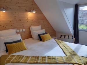 een groot bed in een kamer met een houten muur bij CHARMES EN VILLE Le Charme Authentique in Montluçon