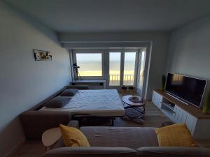a living room with a bed and a flat screen tv at zeedijk westende in Westende